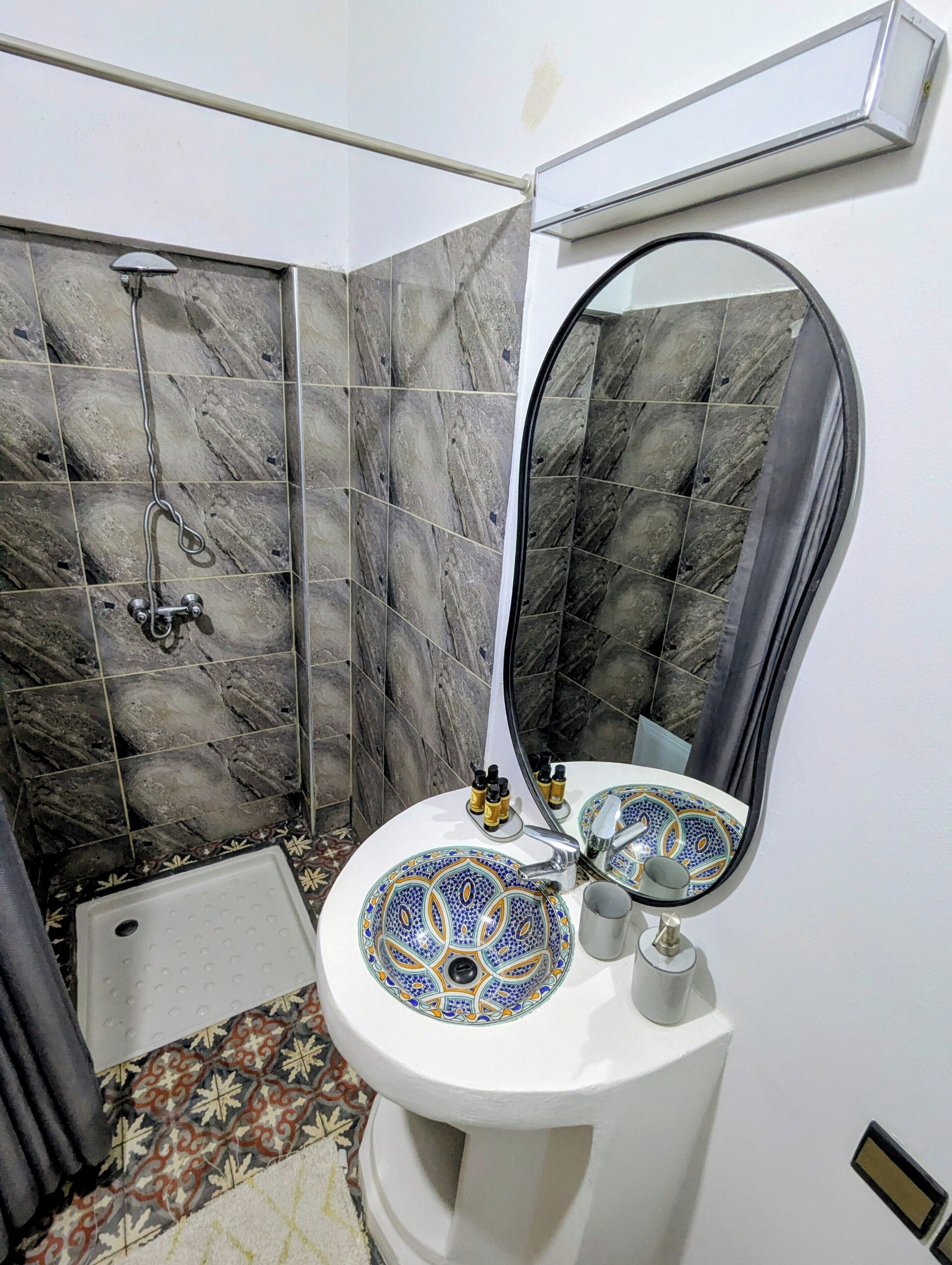 A bathroom with a white sink, a mirror, and a shower area.