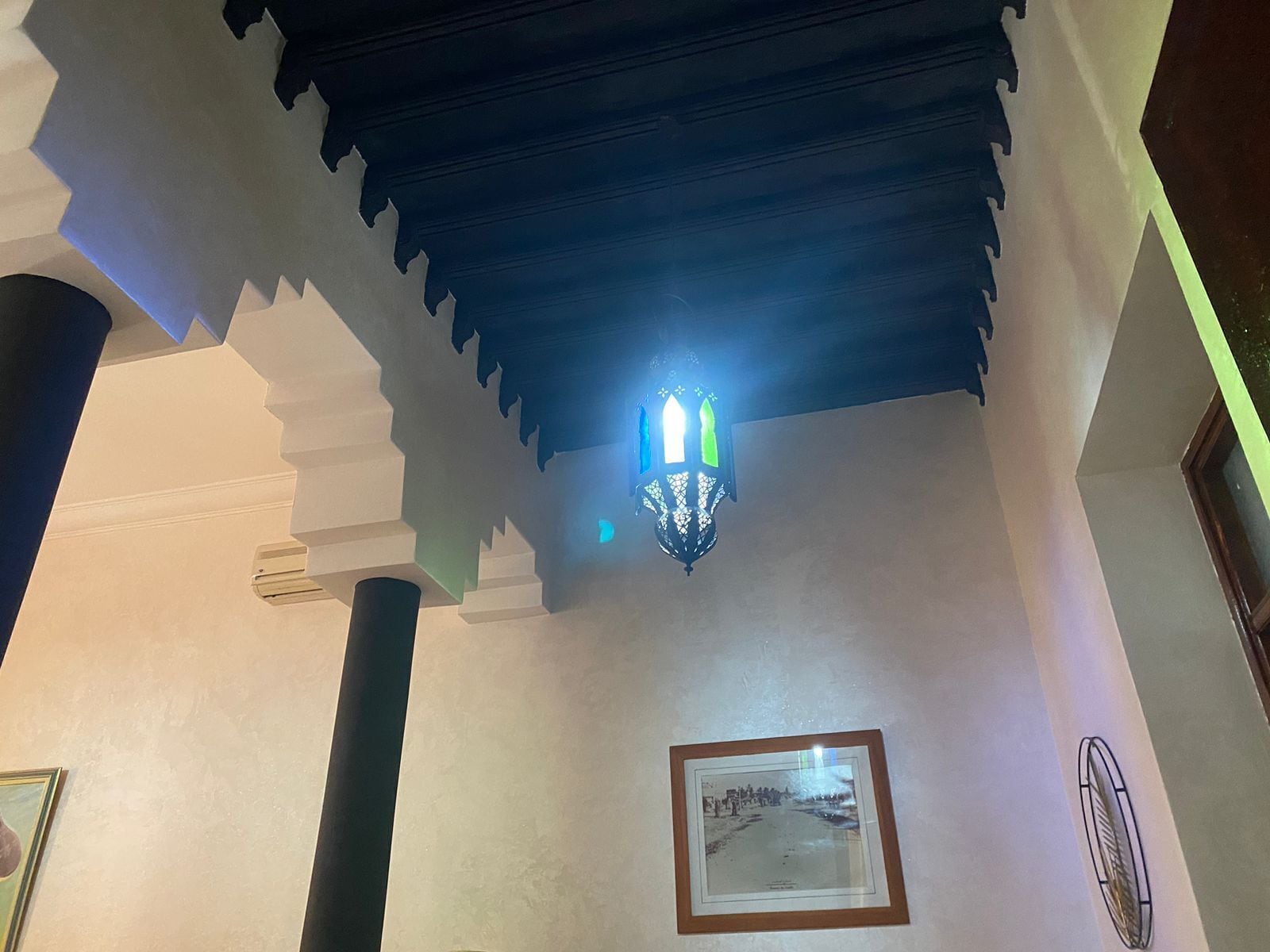 Una habitación con techo decorativo, un cuadro en la pared y una lámpara.
