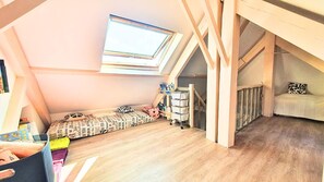 Ein Zimmer mit schrägem Dach, einem Oberlicht, einem Stockbett und einem kleinen Schreibtisch mit Stauraum.