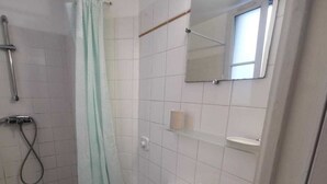 A bathroom with a shower, toilet, sink, and a mirror.