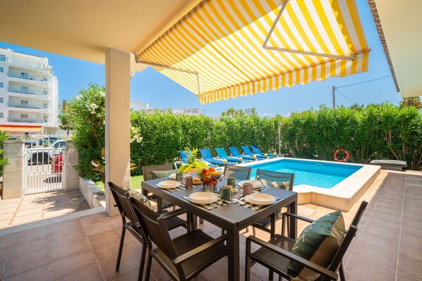 An outdoor dining area with a pool and lounge chairs.