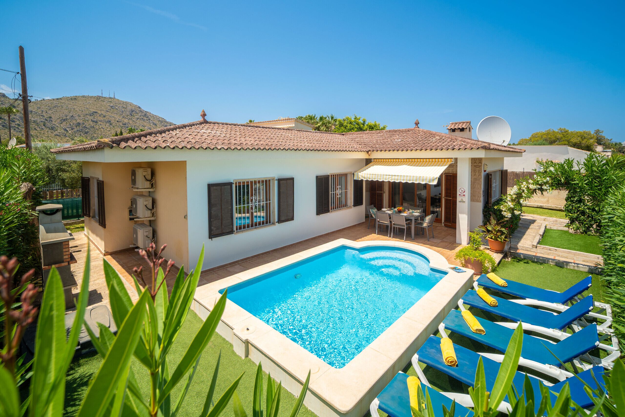Une maison avec une piscine, une terrasse avec des chaises et une antenne parabolique.