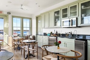 Cozinha com armários verde-claros, eletrodomésticos de aço inoxidável e vista para a marina através de grandes janelas.