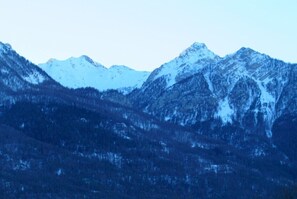 Un paysage montagneux aux sommets enneigés et aux forêts denses.