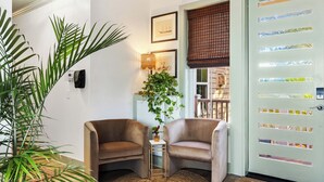 Habitación de esquina con dos sillones, una mesita, una planta en maceta y una puerta con ventana.