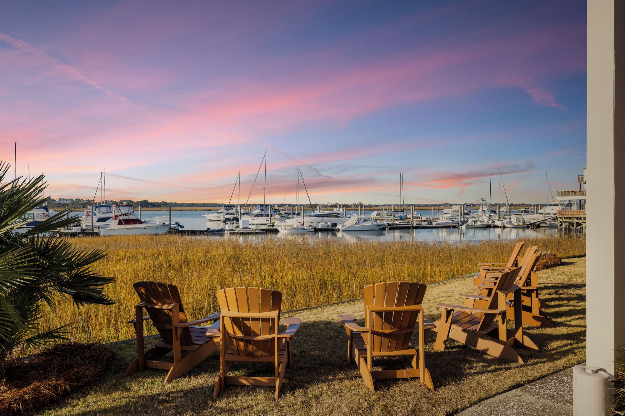 Een jachthaven met boten, stoelen en uitzicht op het water.