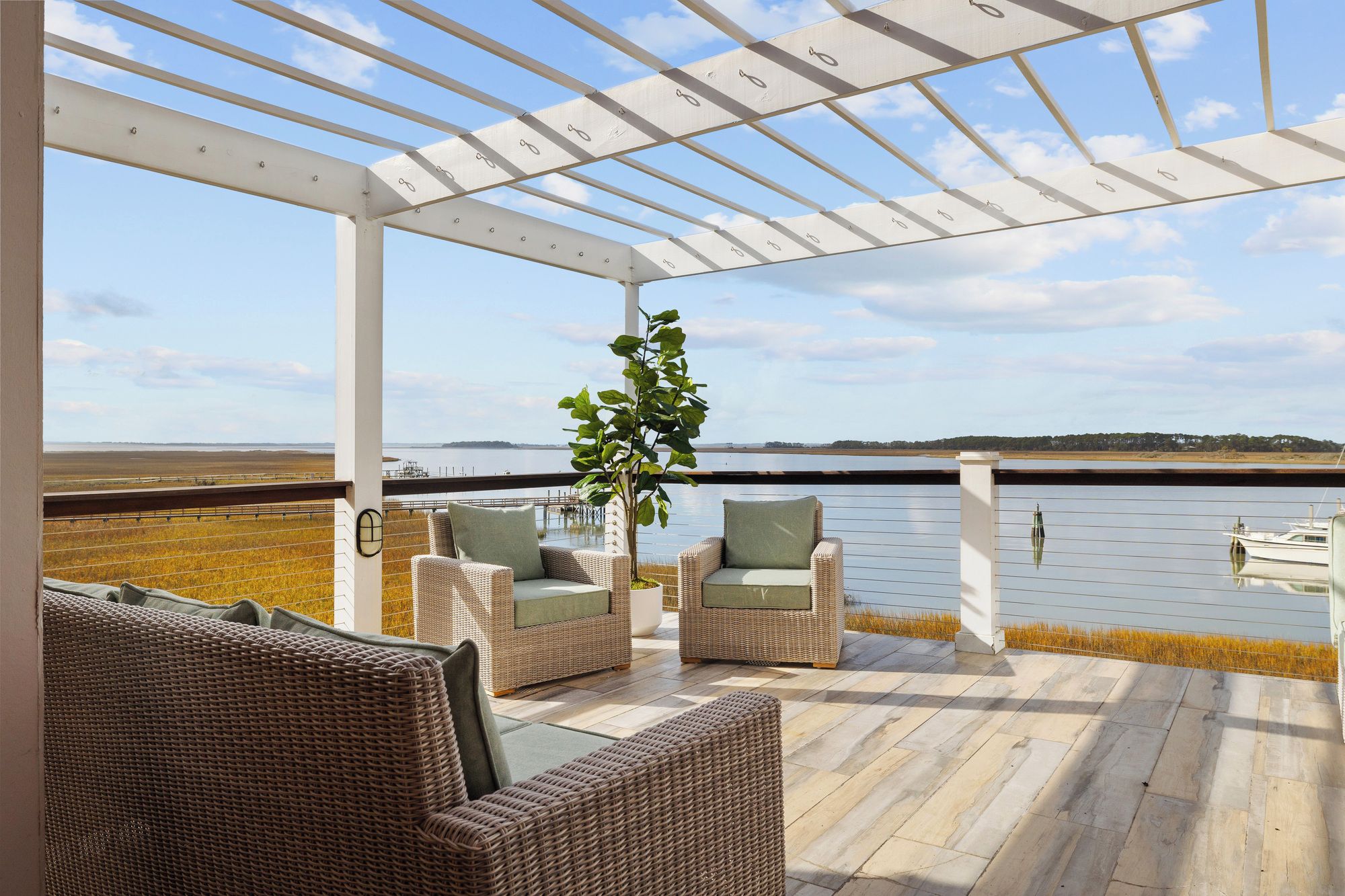 A covered outdoor seating area with wicker furniture and a view of a body of water.