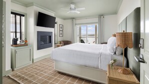 Un dormitorio con cama, televisor montado en la pared, ventilador de techo y ventana con vistas.