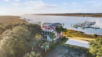 A coastal house with a dock, marina, and surrounding natural landscape.