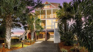 Un hotel de varios pisos con balcón, rodeado de vegetación tropical.