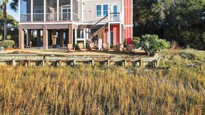Monikerroksinen rakennus, jossa on parvekkeita, katettu ulkoalue istuimineen ja näkymä vesistöön.
