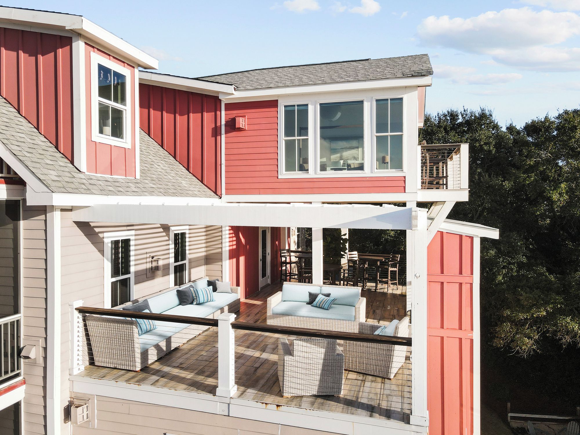 A two-story house with a covered patio area featuring outdoor furniture.