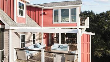 A two-story house with a covered patio area featuring outdoor furniture.