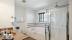 A modern bathroom with a glass-enclosed shower, a bathtub, and a vanity with toiletries. - Make Regatta Inn your Folly Beach home away from home. (Folly Beach)