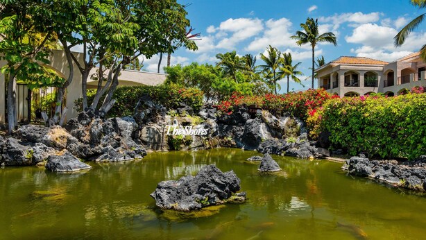 Un resort tropical con un estanque de carpas koi, exuberante vegetación y un cielo azul cristalino.