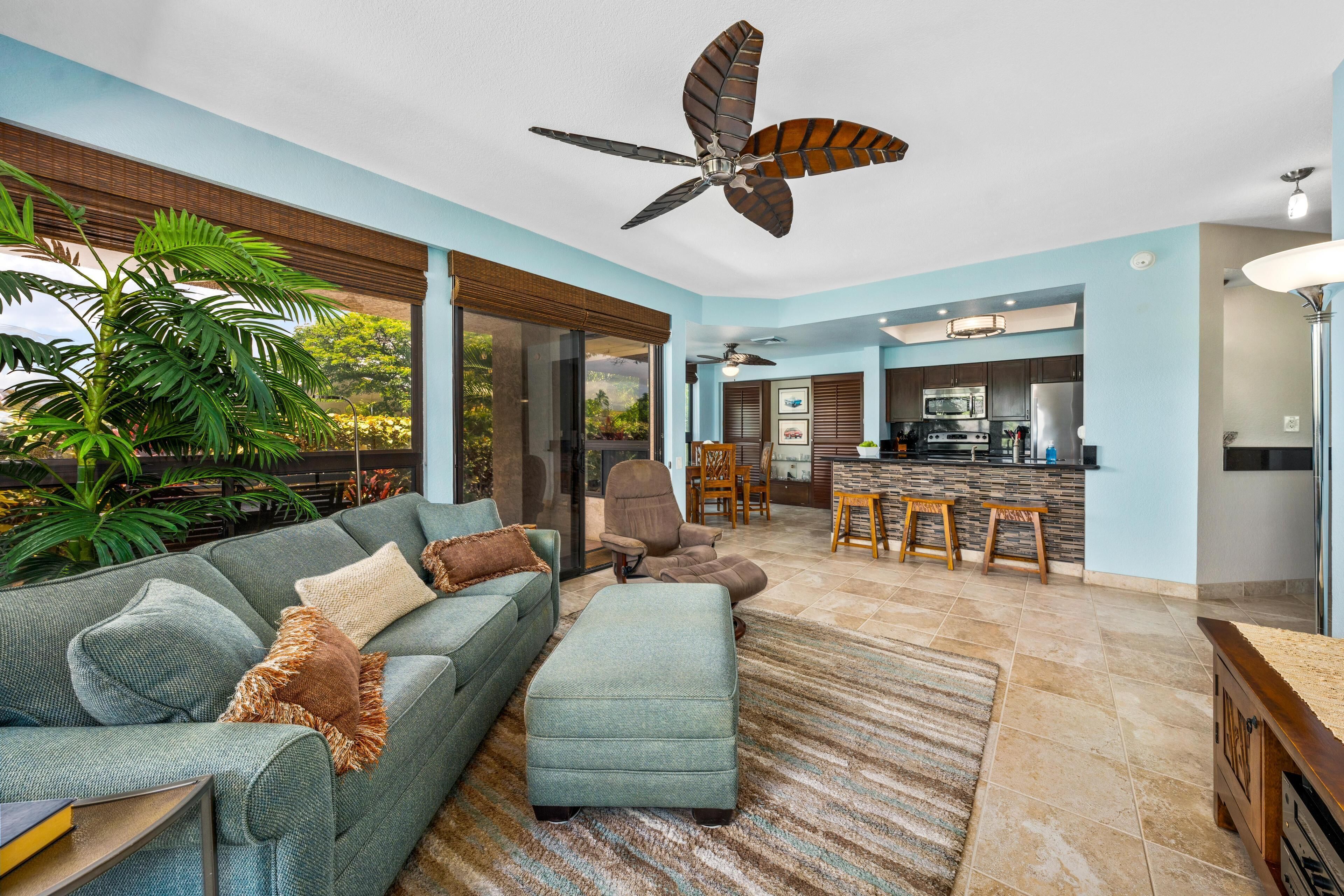 A modern living room with a sofa, ottoman, and a ceiling fan.