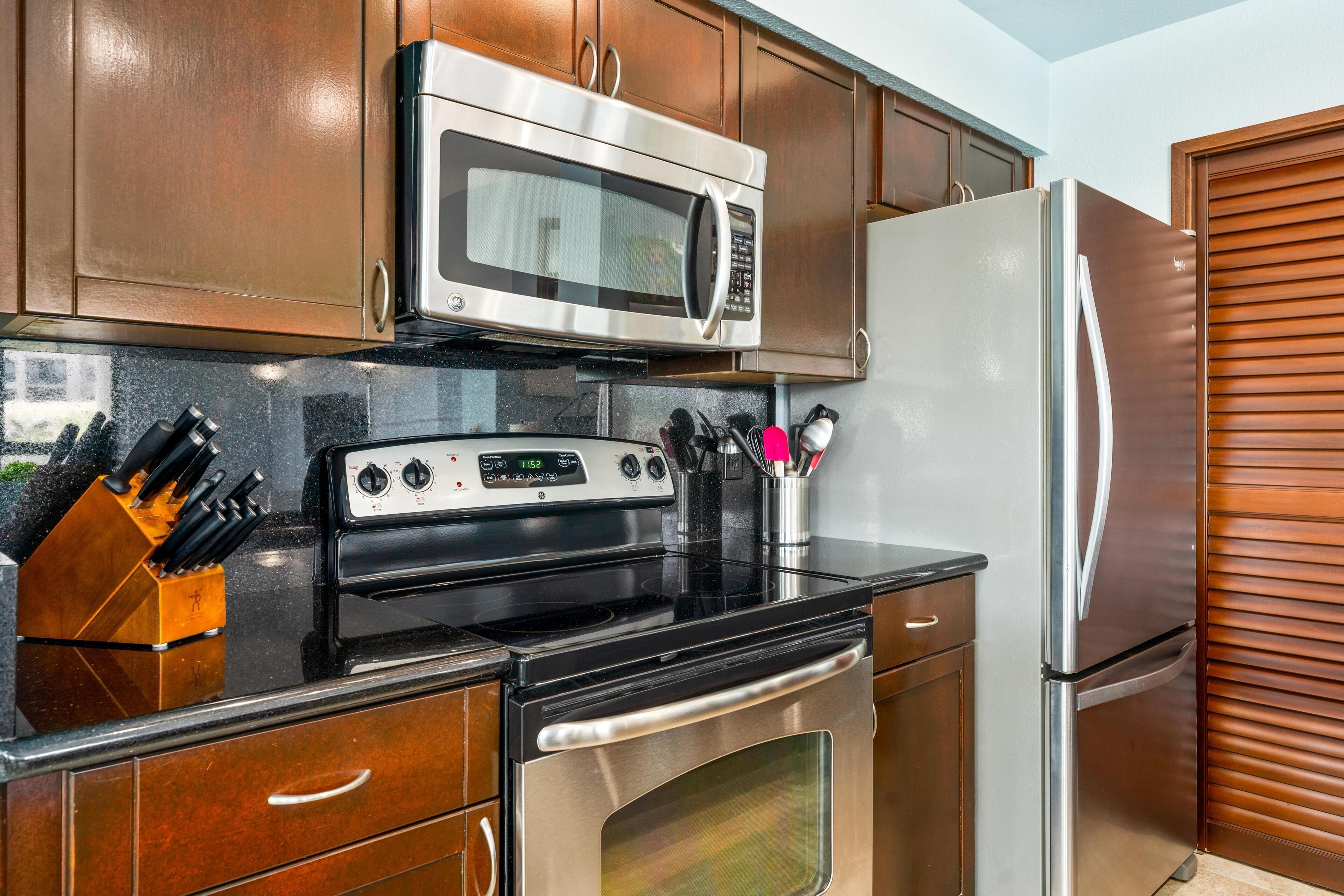 A kitchen with stainless steel appliances, wooden cabinets, and a knife block.