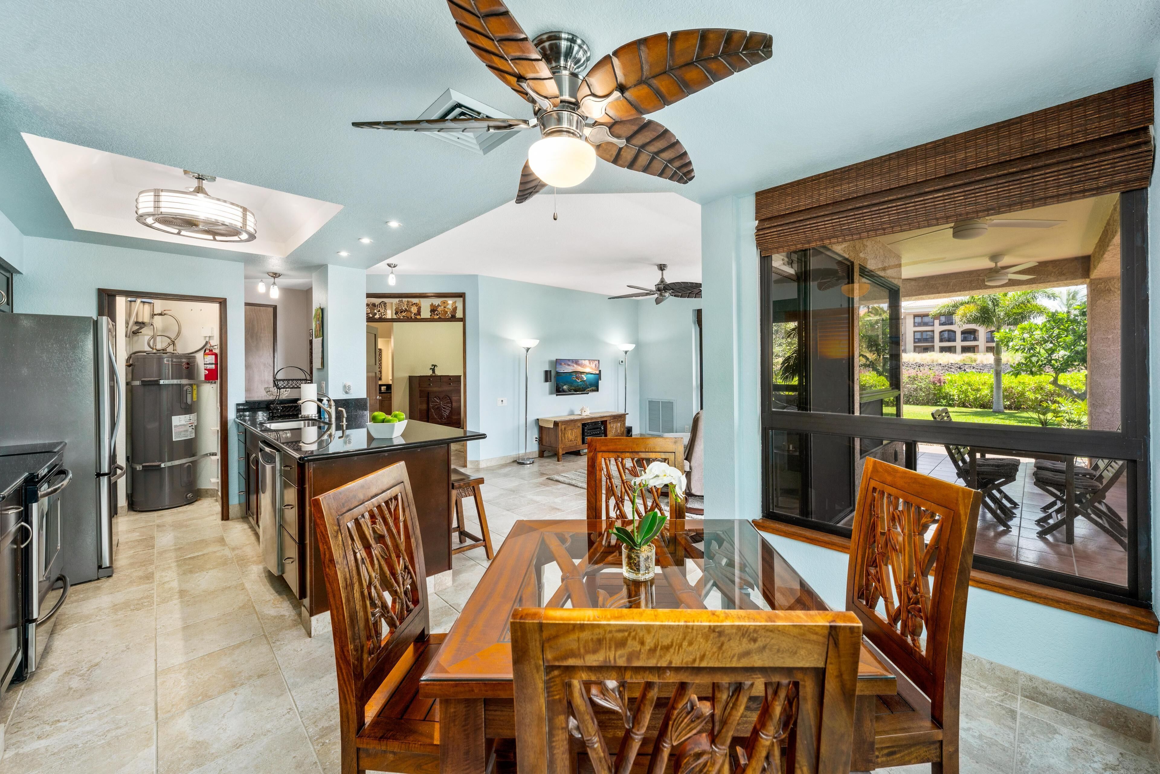 Una cocina moderna con una isla central, un comedor con sillas de madera y un amplio ventanal con vistas a zonas verdes.
