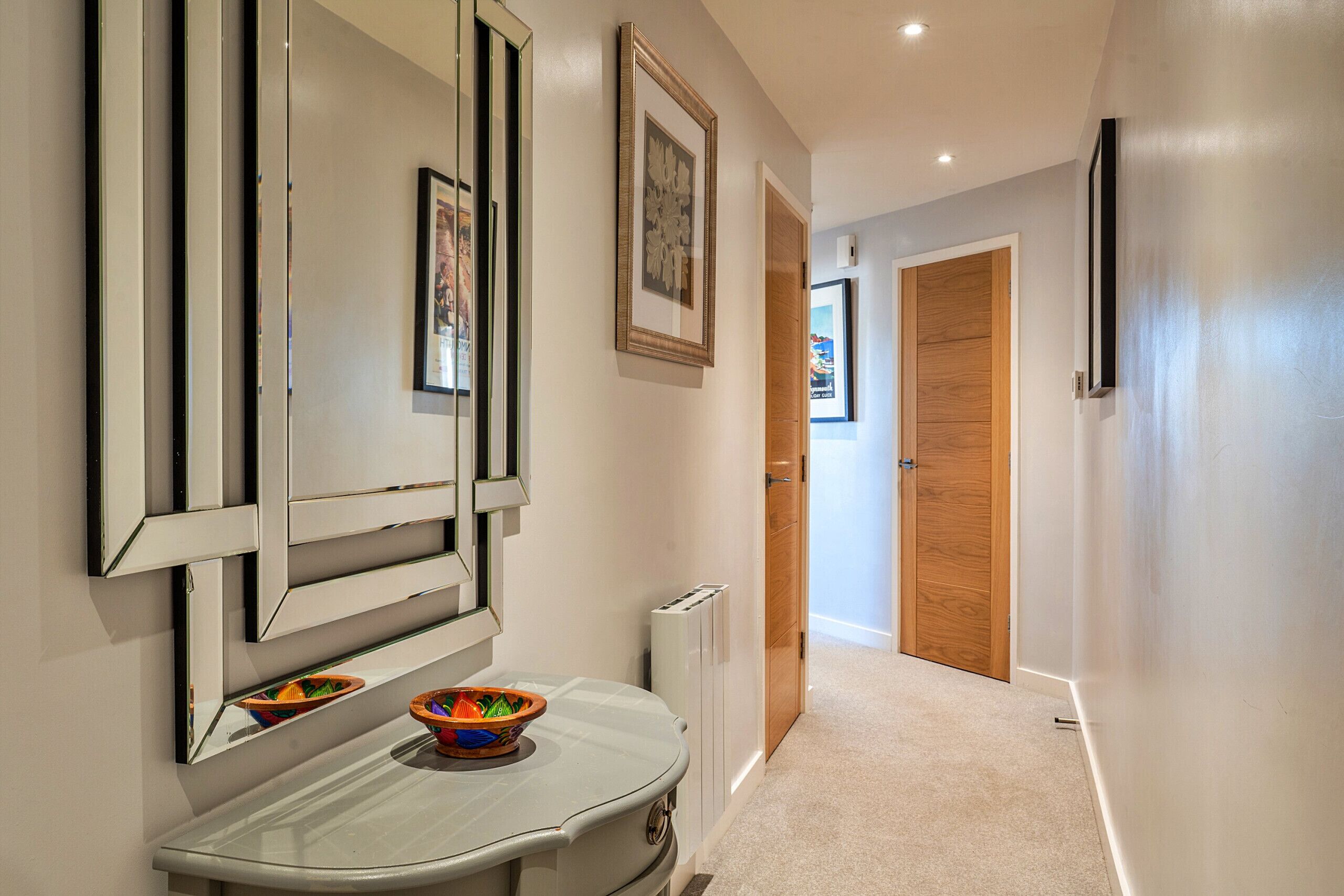 A hallway with a white wall, a wooden door, and a white radiator.