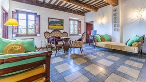 A room with a checkered floor, wooden furniture, a sofa, a table, and a painting on the wall. - Casale Il Farro (Camaiore)