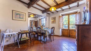 A dining area with a rustic wooden ceiling, tiled floor, and a table set for four. - Casale Il Farro (Camaiore)