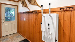 Un pasillo con paneles de madera, un cuadro eléctrico blanco, una puerta con ventanal y un felpudo en el suelo.