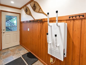 A hallway with wooden paneling, a white electrical panel, a door with a window, and a mat on the floor.