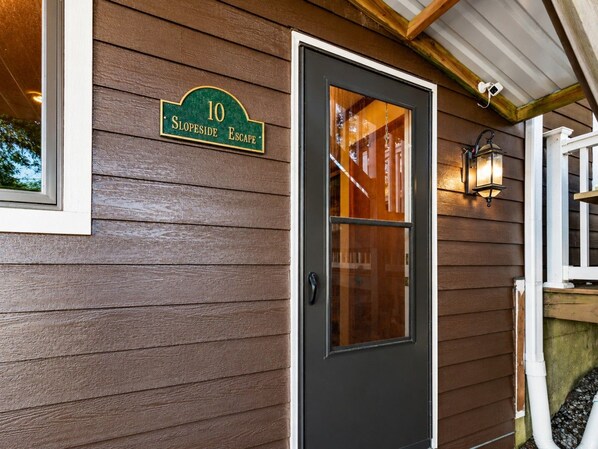 A house number sign, a dark-colored door, and a small porch with a railing.