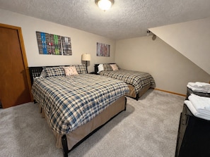 A bedroom with two beds, a door, and a wall with ski-themed artwork. - Slope Side Amazing Location (Snowshoe)