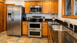 Una cocina moderna con electrodomésticos de acero inoxidable, armarios de madera y encimera de granito.
