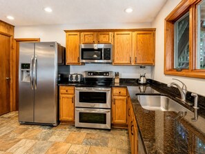 A modern kitchen with stainless steel appliances, wooden cabinets, and a granite countertop.