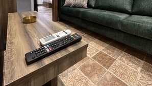 A living room with a green sofa, a wooden coffee table, and a remote control. - 3 Antica jabalal-lwebdeh (Amman)