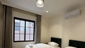 A hotel room with two beds, a window with curtains, a patterned floor, and a ceiling light fixture. - 3 Antica jabalal-lwebdeh (Amman)