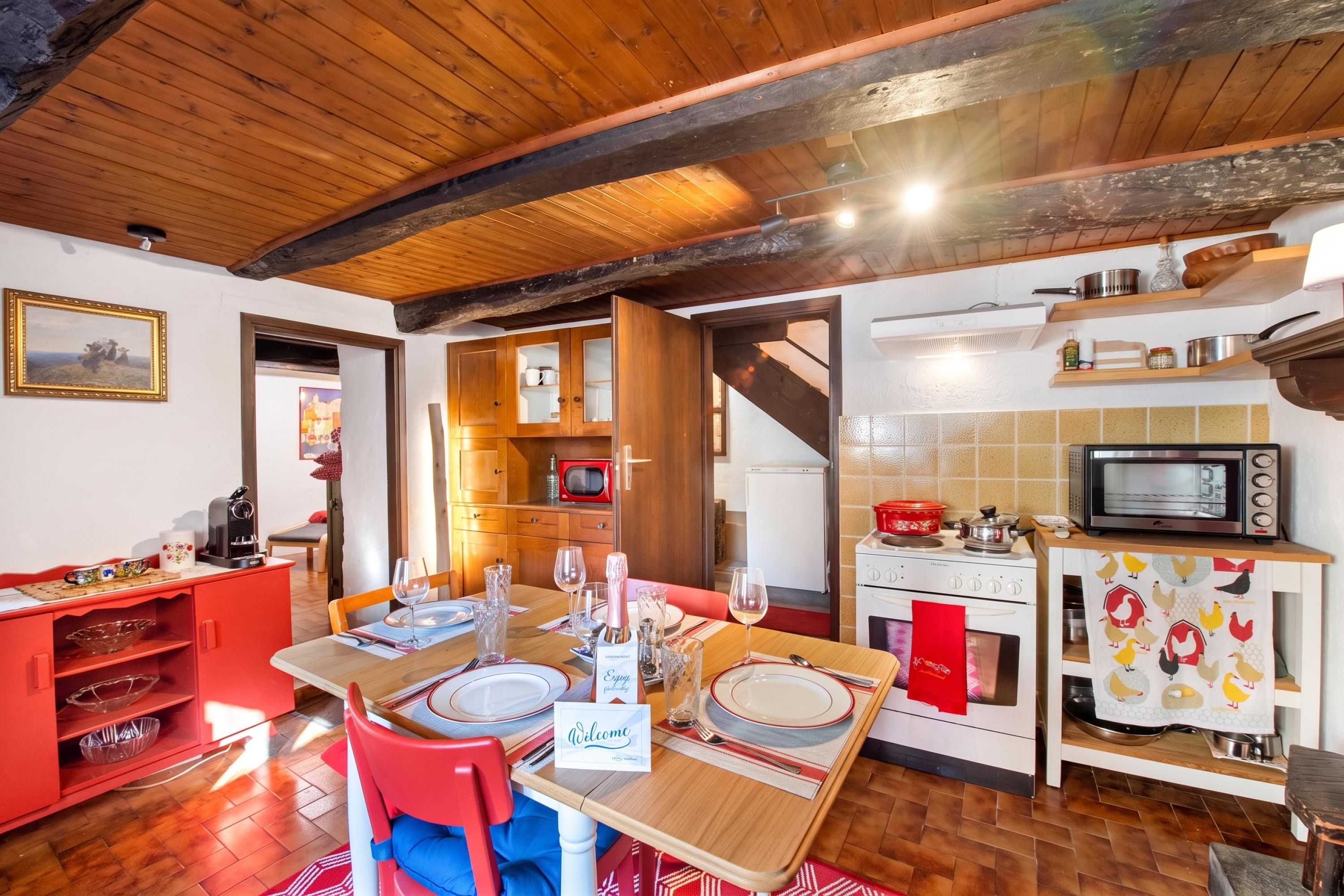 Un comedor con una mesa de madera para dos personas, una silla roja y un cartel que dice 'Welcome'.