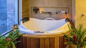 A modern bathroom with a freestanding bathtub, wooden paneling, a shelf with toiletries, and potted plants. - Chalés Realli (Bocaina de Minas)