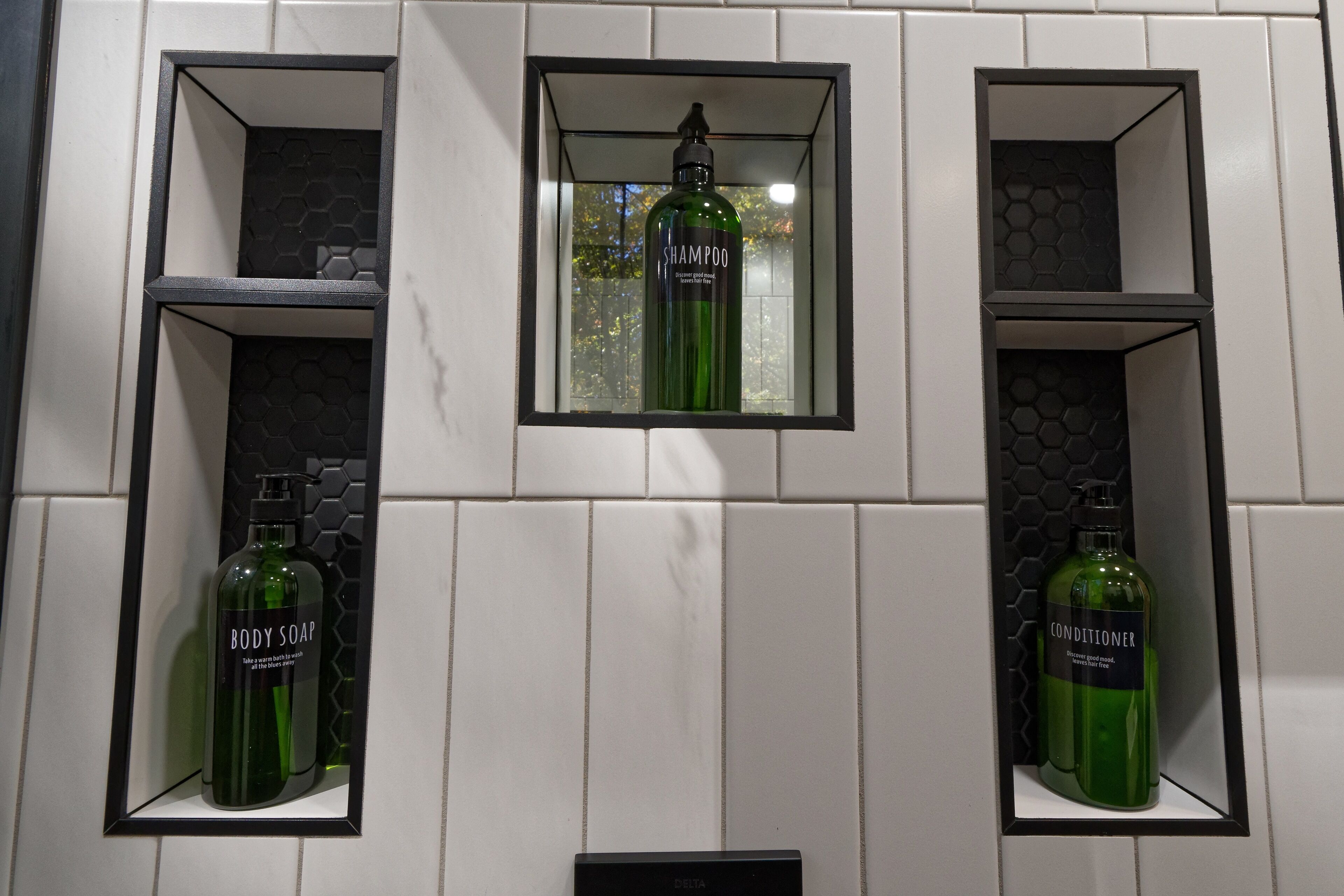 A bathroom with three shelves, each containing a bottle of shampoo and conditioner.