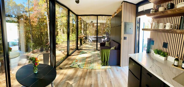 Una cocina moderna con un gran ventanal, suelo de madera y un comedor con mesa y sillas.