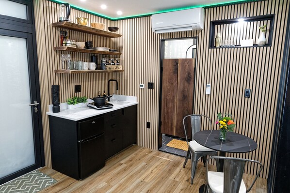 A compact kitchen with wooden paneling, a black refrigerator, and a dining area with a table and chairs.