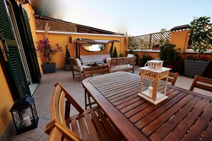Un patio al aire libre con muebles de madera, incluyendo una mesa y sillas, y un pequeño farol.