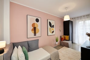 Un salón moderno con un sofá, una mesita con una lámpara y dos cuadros abstractos en la pared.