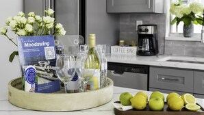 A kitchen with grey cabinets, a coffee maker, and a sign indicating a coffee bar.