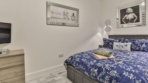 A bedroom with a bed, a dresser, a TV, and two framed pictures on the wall.