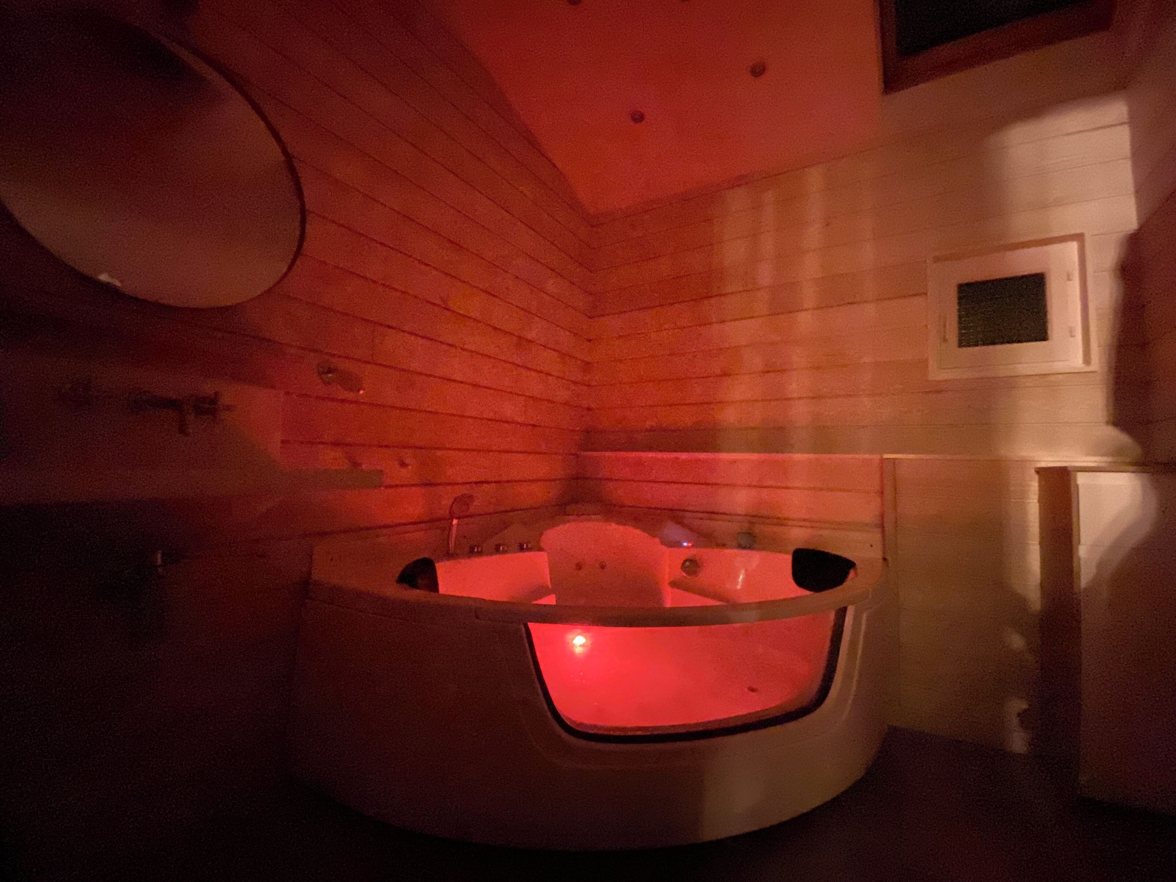 L’intérieur d’un chalet en bois, avec une baignoire en bois et une petite fenêtre.