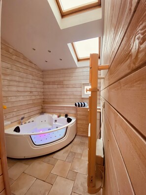 A modern bathroom with a freestanding bathtub, wooden panel walls, and a skylight.
