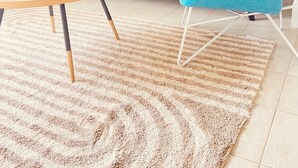 Una sala de estar con un sofá color turquesa, una mesa redonda de madera y un sillón azul. Hay dos lámparas fijadas a la pared.