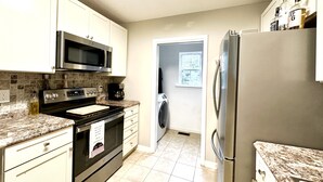 Una cocina moderna con electrodomésticos de acero inoxidable, microondas, cafetera y refrigerador.