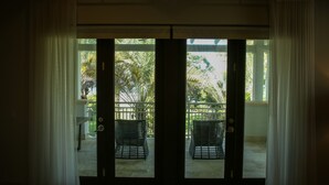 A room with a sliding glass door leading to an outdoor area with two wicker chairs and a metal railing. - Waking up in a tropical reserve with the sound of the sea caressing your soul. (Río Grande)