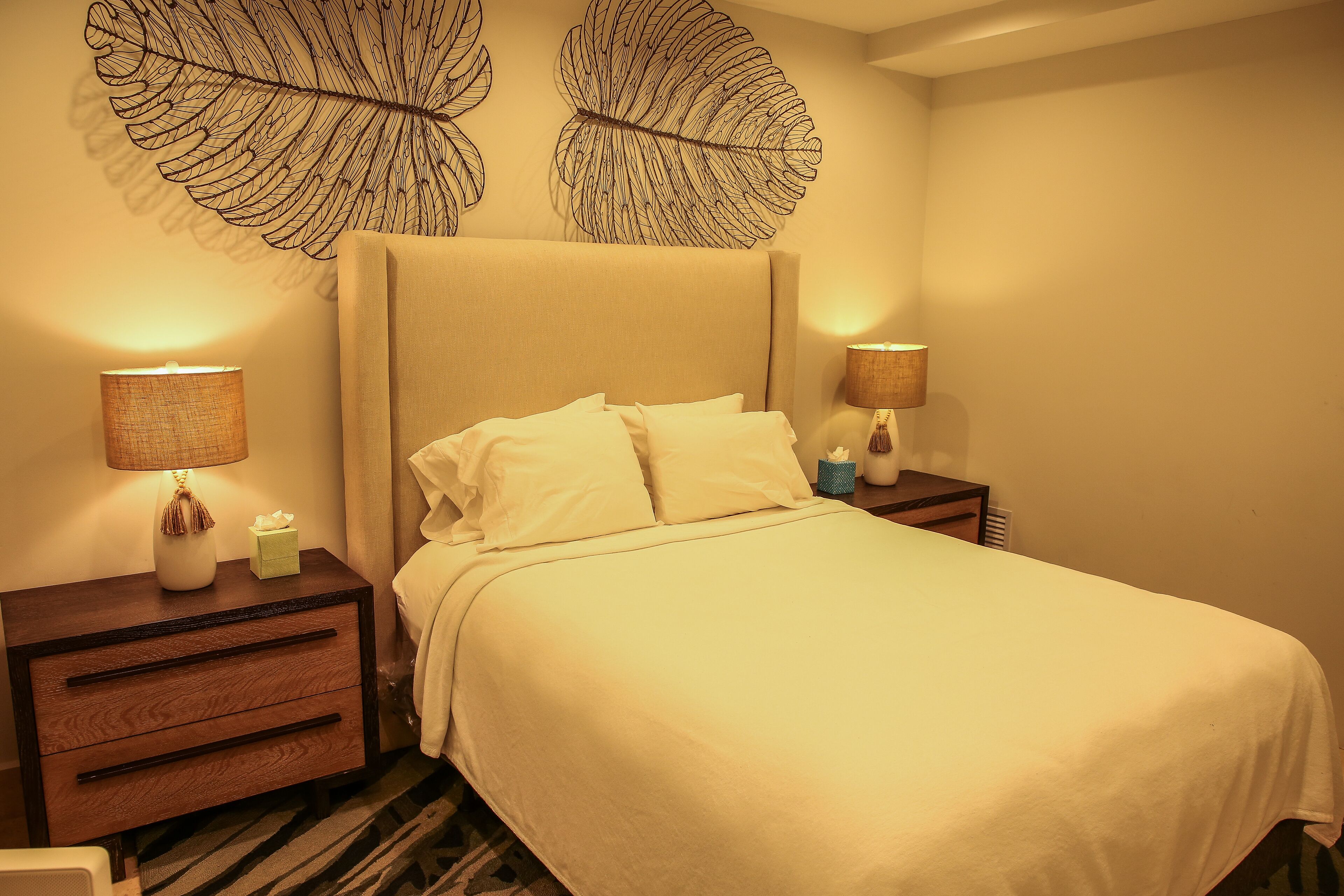 A hotel room with a large bed, two bedside tables with lamps, and decorative wall art.