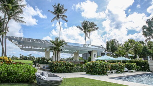 A pool area with a lounge chair, a covered seating area, and a solar panel structure. - Waking up in a tropical reserve with the sound of the sea caressing your soul. (Río Grande)