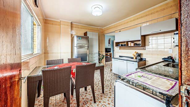A compact kitchen with a dining area, a refrigerator, and a coffee machine. - Agradável apartamento no Caiçara (Praia Grande)